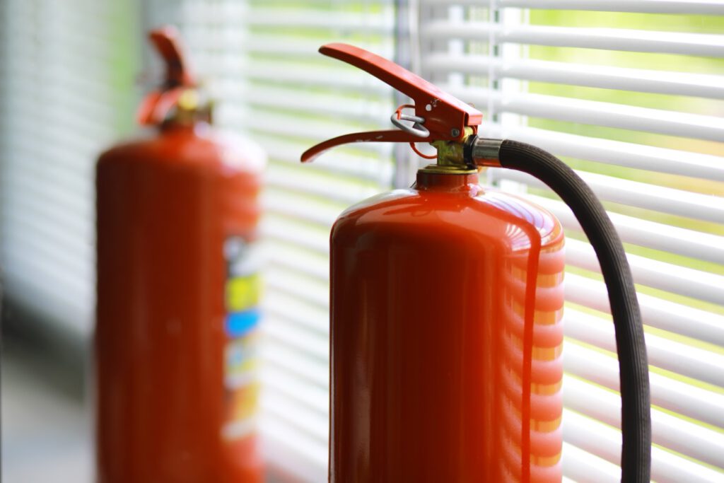 Zwei Feuerlöscher vor einem Fenster