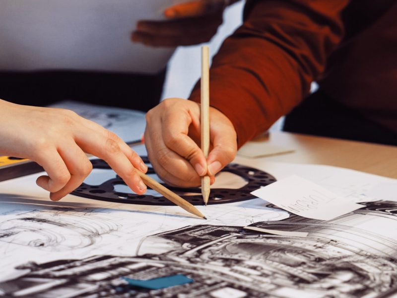 A,Group,Of,Engineers,Collaborates,On,Intricate,Blueprints,Of,Mechanical